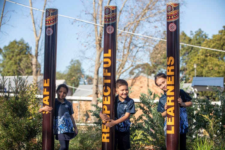 Students surrounded by the safe, respectful and learners poles.